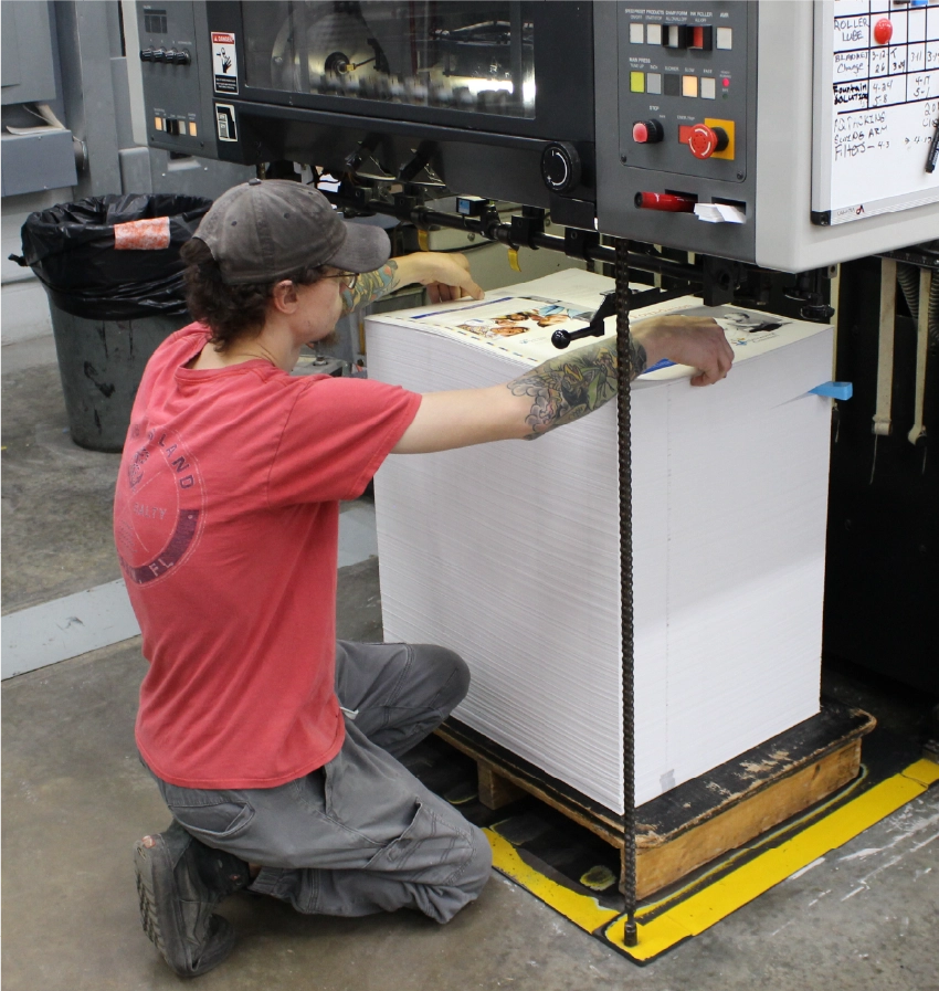Commercial printer loading paper into offset press