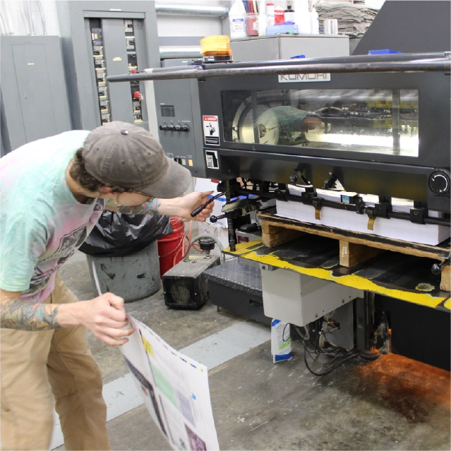 Press operator inspecting printed sheets
