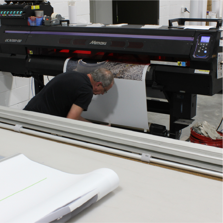 Wide format printer worker checking freshly printed banner at PXPOHIO in Columbus