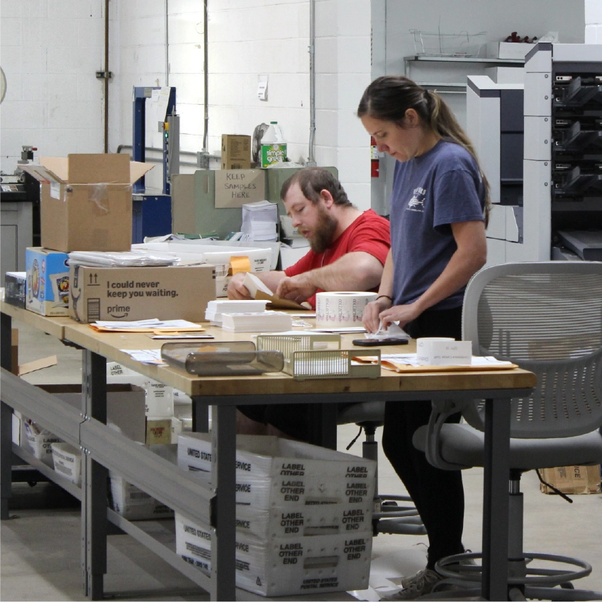 Technician operating mail insertion machine for direct mail assembly
