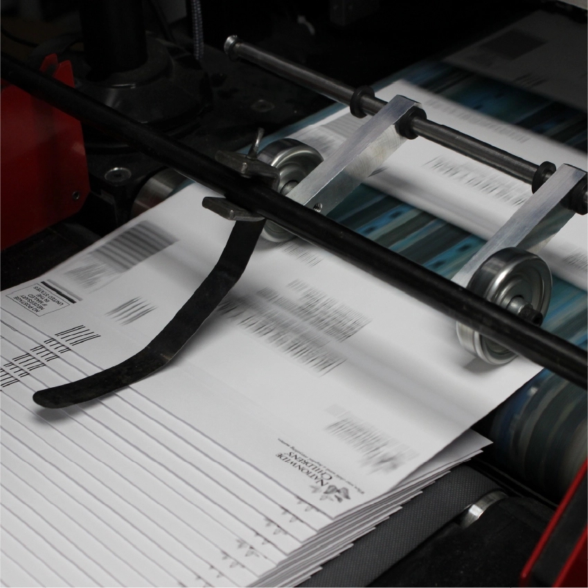 Worker inspecting printed sheets on commercial offset press